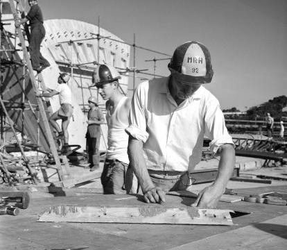 A group of five people in hard hats working on the construction site of the Sydney Opera House.