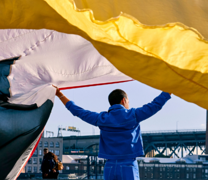 A man holding a long colourful curtain.