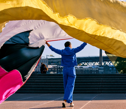 A man holding a long colourful curtain.