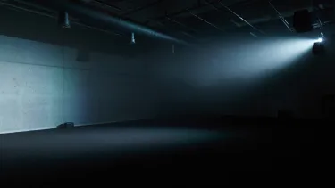 An empty concrete room with a light projecting onto the walls.