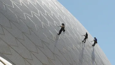 Sydney opera house staff inspecting the tiles on the sails of the building.