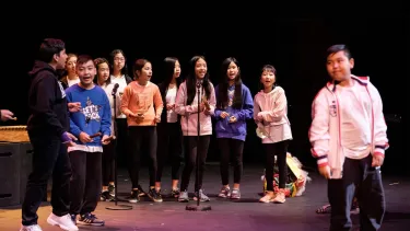 A group of children singing in to a microphone.