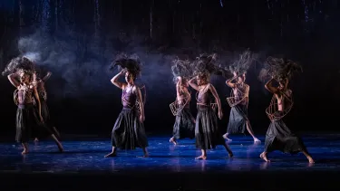 A group of dancers performing a traditional Aboriginal dance on a stage.