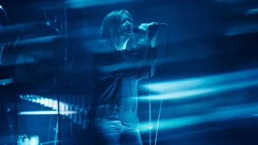 Beth Gibbons singing into a microphone held up by a microphone stand.