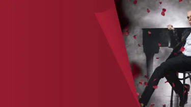 A bald man in a black suit with roses in the air.