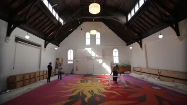 Three men assessing the Tapestry cloth in a warehouse.