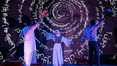 Two men and a woman on a stage holding books.