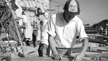 A group of five people in hard hats working on the construction site of the Sydney Opera House.