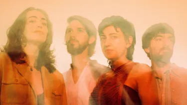 Two men and two women pose, washed in orange light.