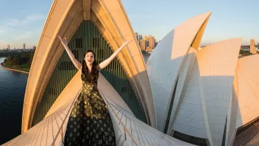 An opera singer standing on the sails of the Opera House.
