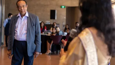 A man in a suit facing a woman in a gold dress.