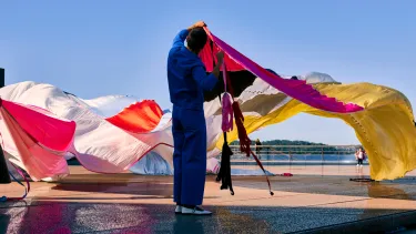 A man holding a long colourful curtain.