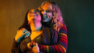 Two women embracing, one with dark hair, one with light hair.