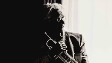 Håkan Hardenberger holds a trumpet in dramatic black and white lighting.