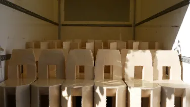 A group of cream chairs with a square cut out in the back sit inside a room.