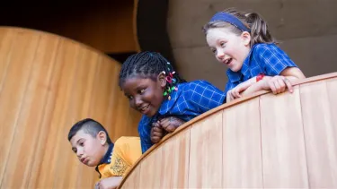 Three students peer over a balcony at the Opera House.