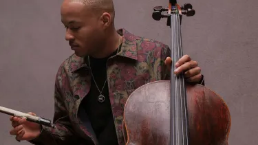 Sheku Kanneh-Mason with a floral jacket holding his Cello.
