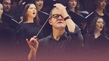 A conductor stands in front of a choir.