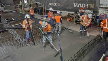 Construction workers pouring concrete into the new steel frame of the stage.