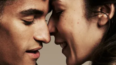 Two dancers with their faces close to touching, eyes closed.