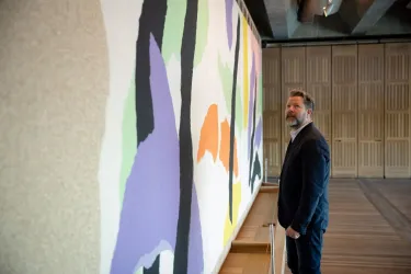 A man in a suit staring at artwork on a wall.